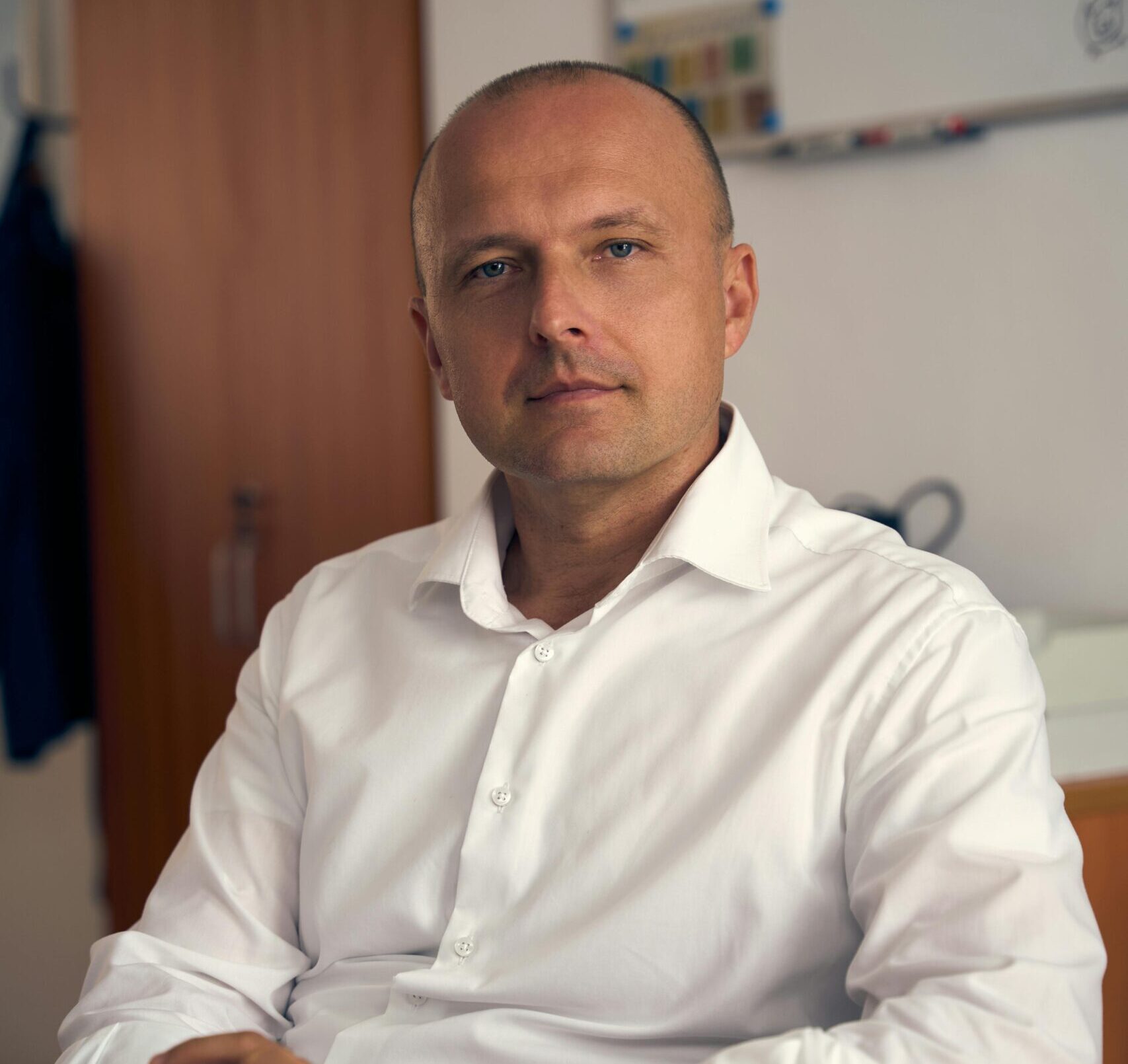 Confident professional posing for a portrait in a modern office environment.